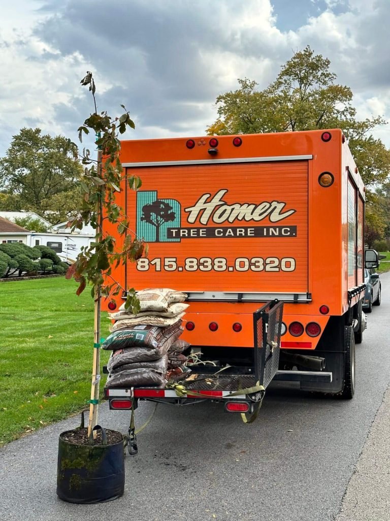 Homer Tree Care truck and trailer with tree and soil bags for tree planting services. Call 815-838-0320.